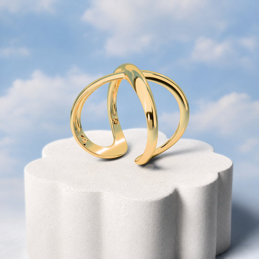 Anel Aurora - Infinito: sobre pedestal de gesso em forma de nuvem, fundo de céu azul-claro. Semijoia banhada a ouro 18k, coleção Supernova, Aimer Joias