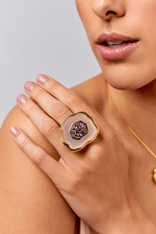 Esta joia combina pureza e brilho intenso, sendo adornada com Ágata Branca, que promove clareza e paz, e Drusa Multicolorida, que garante equilíbrio e harmonia ao visual. Use este anel em Banho de Ouro 18K para celebrar o seu próprio florescer.