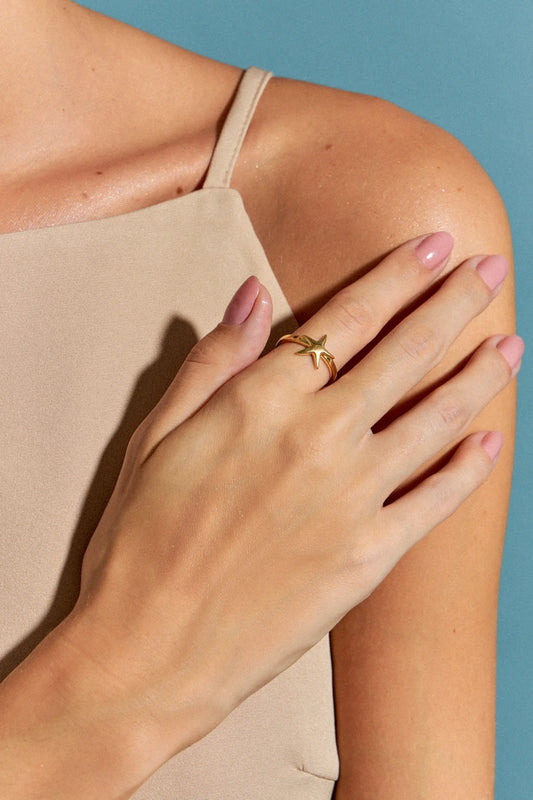 O Anel Estrela em Banho de Ouro 18K é uma pequena estrela-do-mar minimalista. Seu design delicado lembra a beleza serena encontrada nas profundezas do oceano, sendo uma peça versátil e essencial para adicionar um toque de luxo ao dia a dia.