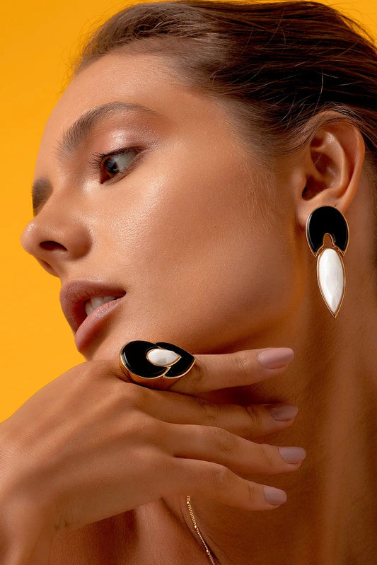 Esta joia apresenta um contraste atemporal de preto e branco, emoldurado pelo luxo do Banho de Ouro 18K. O anel é adornado com a Obsidiana, que oferece proteção e força, e a Porcelana, que adiciona um toque clássico e limpo ao design.