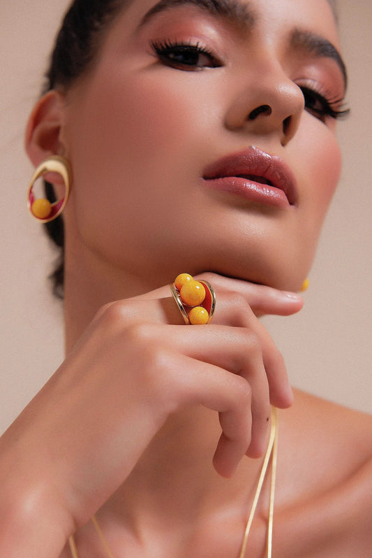 O Anel Sublime em Esmaltado Vermelho e Feldspato Amarelo, com Banho de Ouro 18K, é uma peça vibrante e cheia de personalidade. O Feldspato Amarelo harmoniza-se com o esmalte em tom vermelho, criando um contraste elegante e marcante com o brilho do ouro.