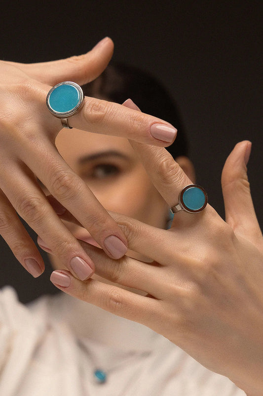 O Anel Único - Ágata Azul Céu, da Coleção Singular, une a serenidade das águas à sofisticação do acabamento escuro. A Ágata Azul Céu é reconhecida por promover calma, clareza mental e harmonia nas emoções, criando um contraste moderno e impactante com o metal escuro. Banhado a Ródio Negro, este anel de design imponente destaca a suavidade da pedra, sendo a peça ideal para mulheres que buscam um acessório contemporâneo que transmita paz interior com uma personalidade forte.