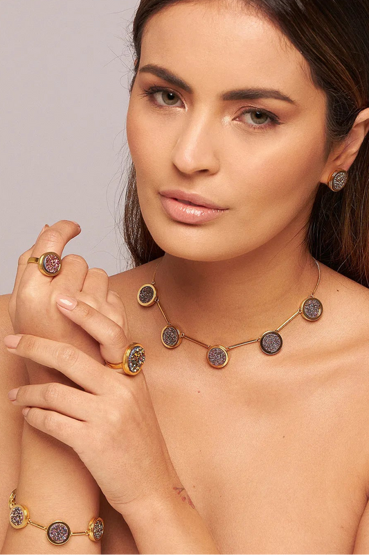 O Anel Único - Drusa Multicolorida é uma peça vibrante da Coleção Singular, que exalta a autenticidade feminina. A Drusa Multicolorida é reconhecida por sua capacidade de revitalizar as energias, promover a criatividade e atrair alegria através do seu espectro variado de cores. Banhado a Ouro 18K, este anel de design imponente destaca o brilho multifacetado da pedra bruta, tornando-se um amuleto de autoconfiança e elegância para qualquer ocasião.