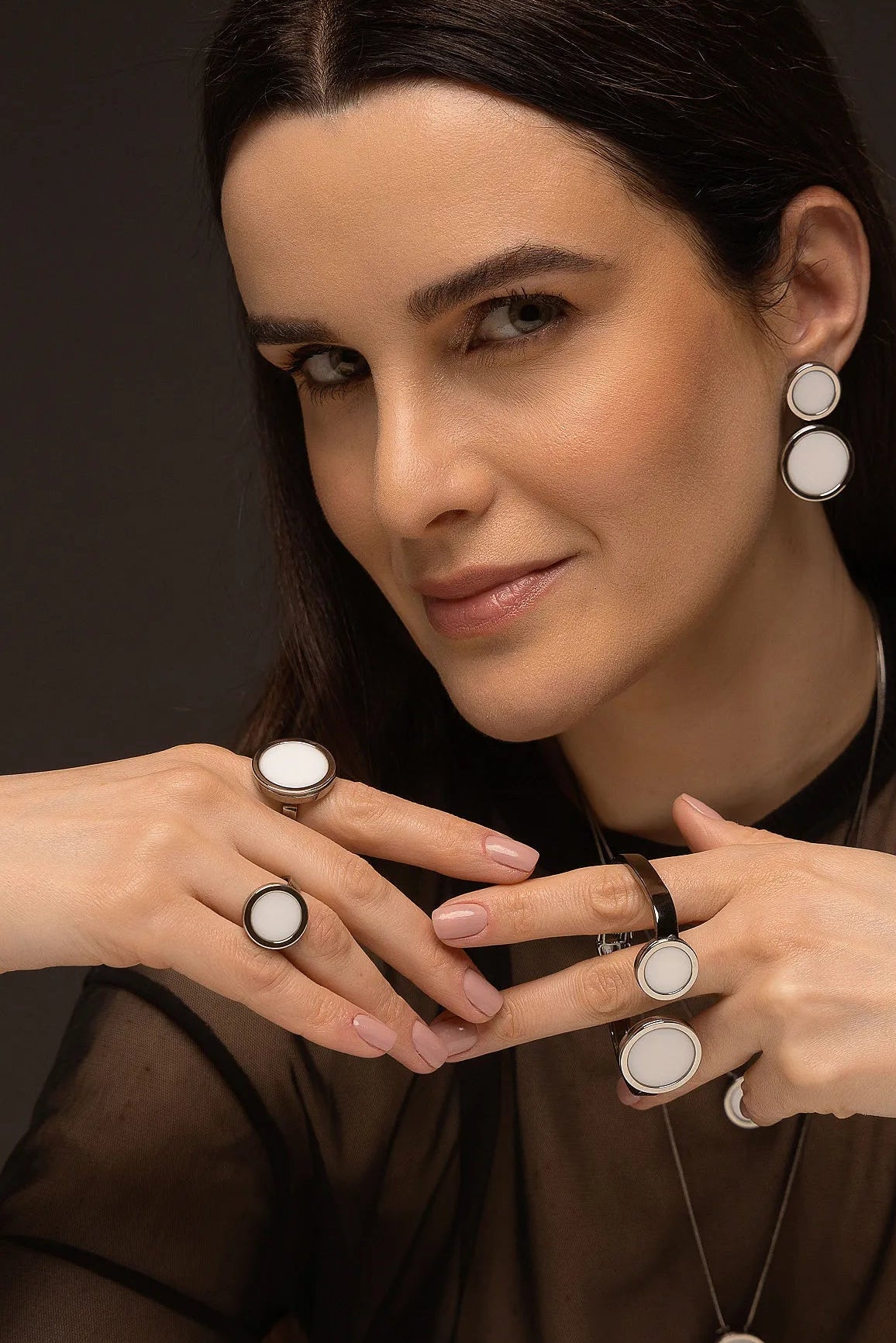 O Anel Único - Porcelana Branca, da Coleção Singular, une a pureza do branco ao mistério do acabamento escuro. A Porcelana Branca simboliza renovação, clareza e paz interior, criando um contraste moderno e sofisticado com o metal escuro. Banhado a Ródio Negro, este anel de design imponente destaca o brilho suave da pedra lisa, sendo a peça ideal para mulheres que buscam acessórios contemporâneos que transmitem serenidade com uma personalidade marcante.