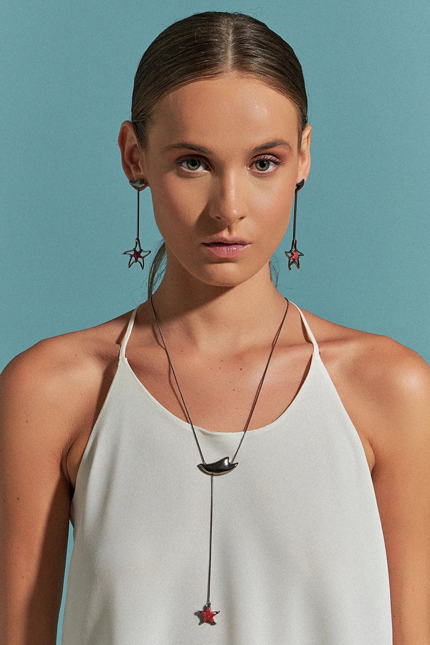 Use o Brinco Brisa com Feldspato Vermelho em Banho de Ródio Negro, criando um contraste dramático e luxuoso entre o tom vibrante da pedra e o acabamento escuro e moderno do ródio.