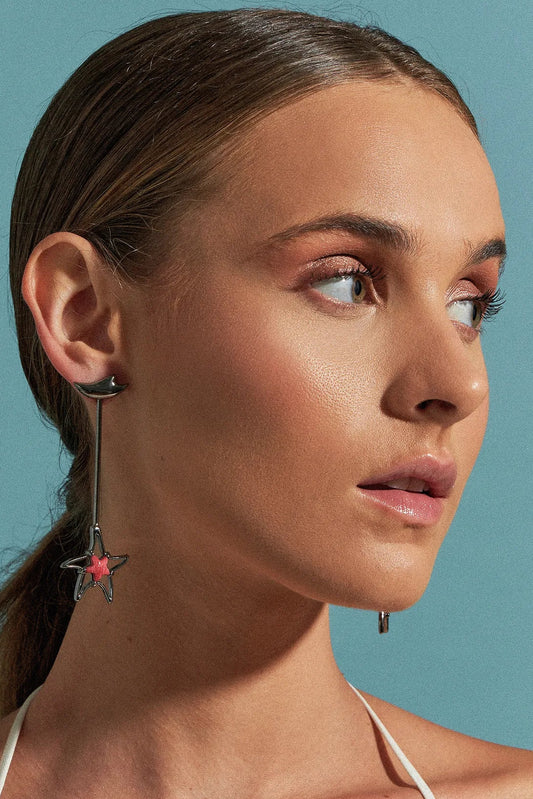 Use o Brinco Brisa com Feldspato Vermelho em Banho de Ródio Negro, criando um contraste dramático e luxuoso entre o tom vibrante da pedra e o acabamento escuro e moderno do ródio.