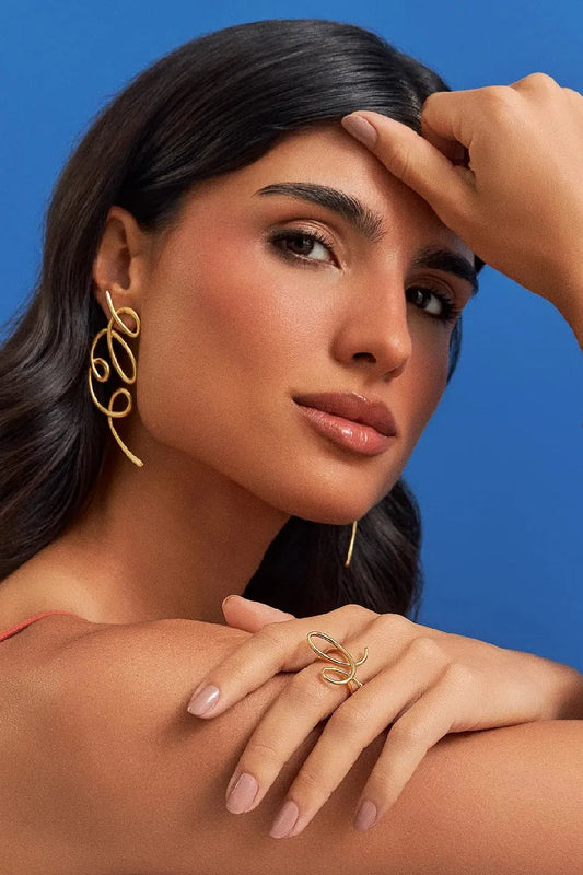 O Brinco Traços em Banho de Ouro 18K é uma joia escultural e assimétrica, inspirada em linhas livres que se encontram, criando volumes fluidos. Um lembrete de que o belo não nasce do controle absoluto, mas do gesto que ousa sair do traço e encontra uma nova forma de ser. São peças leves, expressivas e cheias de movimento.