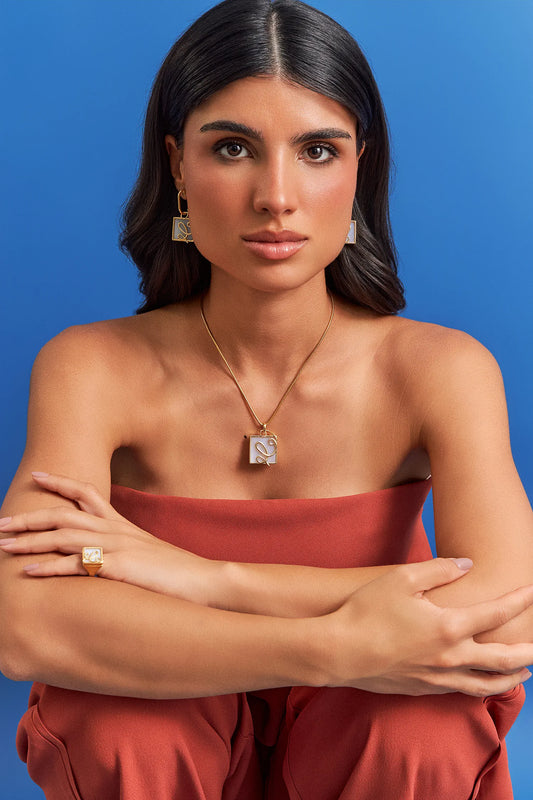 O Colar Forma com Ágata Branca em Banho de Ouro 18K traduz o ponto em que o traço ganha direção. A pedra quadrada de Ágata Branca, que simboliza serenidade e paz, recebe a aplicação de linhas em metal que se cruzam, criando uma linguagem super contemporânea. Com sua corrente robusta, é uma peça moderna e sofisticada, ideal para quem busca equilíbrio e clareza.