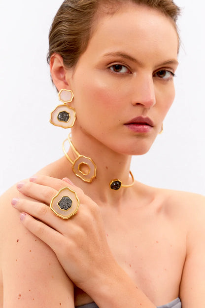 Esta joia combina o contraste de cores clássico com forte simbologia, sendo adornada com Ágata Branca, que promove a paz e a clareza, e Drusa Negra, que atrai energia positiva e proteção. Use este anel em Banho de Ouro 18K para celebrar o seu próprio florescer com elegância.