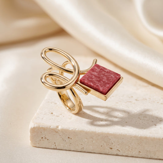 Anel Esboço Feldspato Vermelho banhado a ouro 18k em vista 3/4 sobre travertino | Aimer Joias