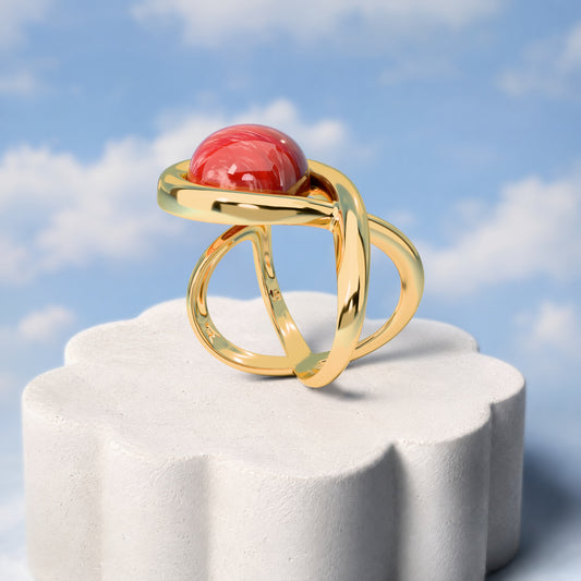 Anel Supernova - Feldspato Vermelho: sobre pedestal de gesso em forma de nuvem, fundo de céu azul-claro. Semijoia banhada a ouro 18k, coleção Supernova, Aimer Joias