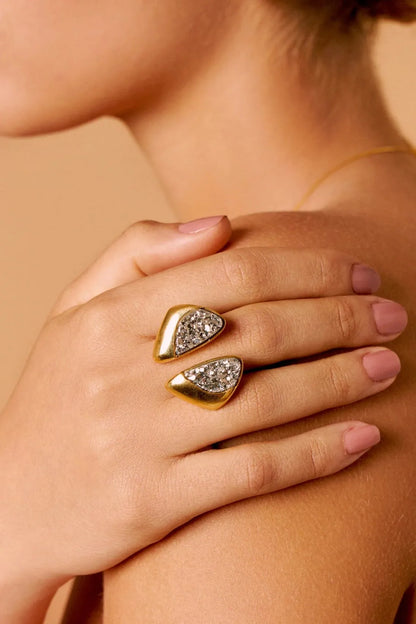 O Anel Ailes com Drusa Platina em Banho de Ouro 18K é uma joia escultural que remete às asas da borboleta. Sua superfície cintilante e o banho dourado criam um visual luxuoso, atemporal e de grande presença.