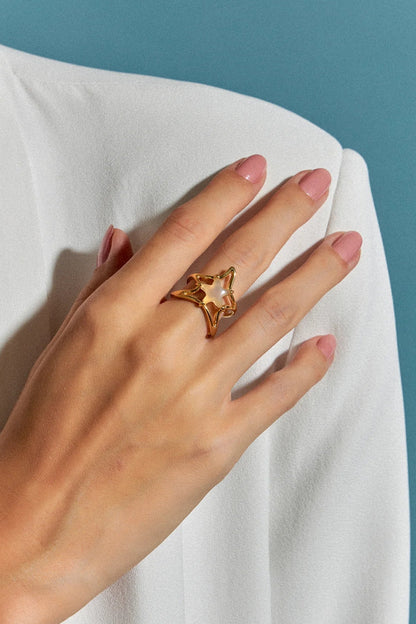 O Anel Brisa com Ágata Branca em Banho de Ouro 18K é uma joia delicada, com uma estrela central em meio a uma onda fluida que a sustenta. A pureza da Ágata Branca é realçada pelo luxo do ouro, criando um visual sofisticado e marcante.