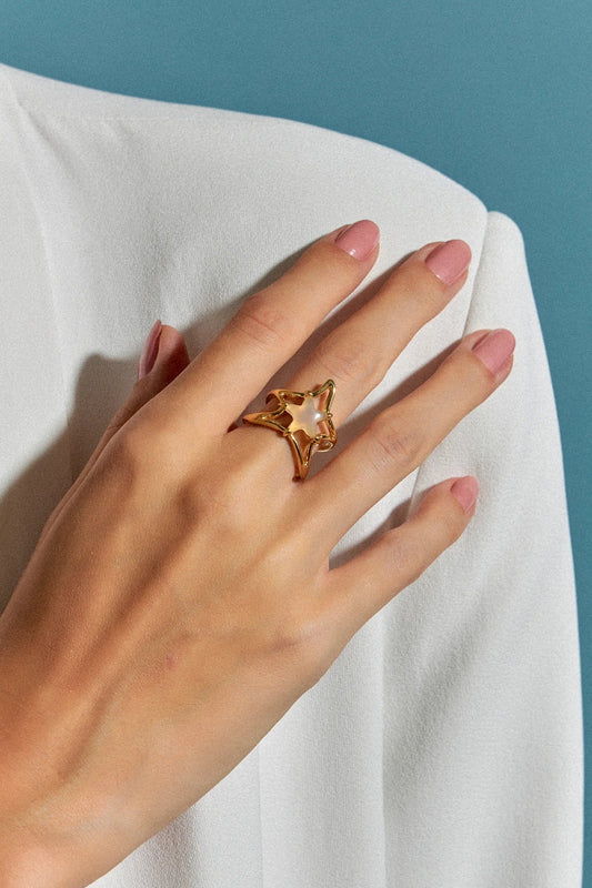 O Anel Brisa com Ágata Branca em Banho de Ouro 18K é uma joia delicada, com uma estrela central em meio a uma onda fluida que a sustenta. A pureza da Ágata Branca é realçada pelo luxo do ouro, criando um visual sofisticado e marcante.