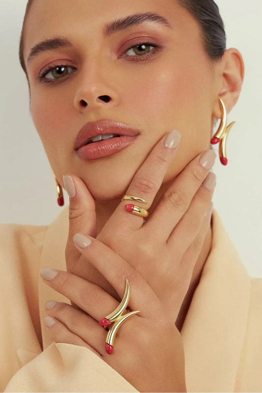 O Anel Caminhos com Feldspato Vermelho e Banho de Ouro 18K é uma joia de alto impacto. O tom vibrante e sedutor do Feldspato Vermelho Cabochão é realçado pelo brilho inconfundível do Ouro 18K, conferindo presença e poder a quem usa.