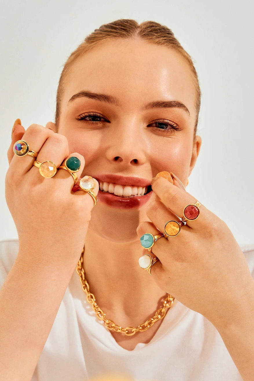 O luxo e a paixão dos Clássicos Aimer. Anel solitário com Feldspato Vermelho Facetado e Banho Ouro 18K. Uma joia icônica que se destaca pela cor intensa e elegante.