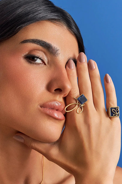 O Anel Esboço com Sodalita em Banho de Ouro 18K traduz a união entre linhas e formas, em um desenho limpo e simbólico. A pedra quadrada de Sodalita, que se equilibra de forma leve no traço orgânico da peça, simboliza clareza e intuição. O equilíbrio entre a forma geométrica da pedra e o traço orgânico do aro confere à peça um charme contemporâneo, perfeito para destacar sua mão com sofisticação.