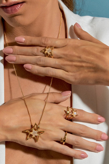 O Anel Estrela em Banho de Ouro 18K é uma pequena estrela-do-mar minimalista. Seu design delicado lembra a beleza serena encontrada nas profundezas do oceano, sendo uma peça versátil e essencial para adicionar um toque de luxo ao dia a dia.