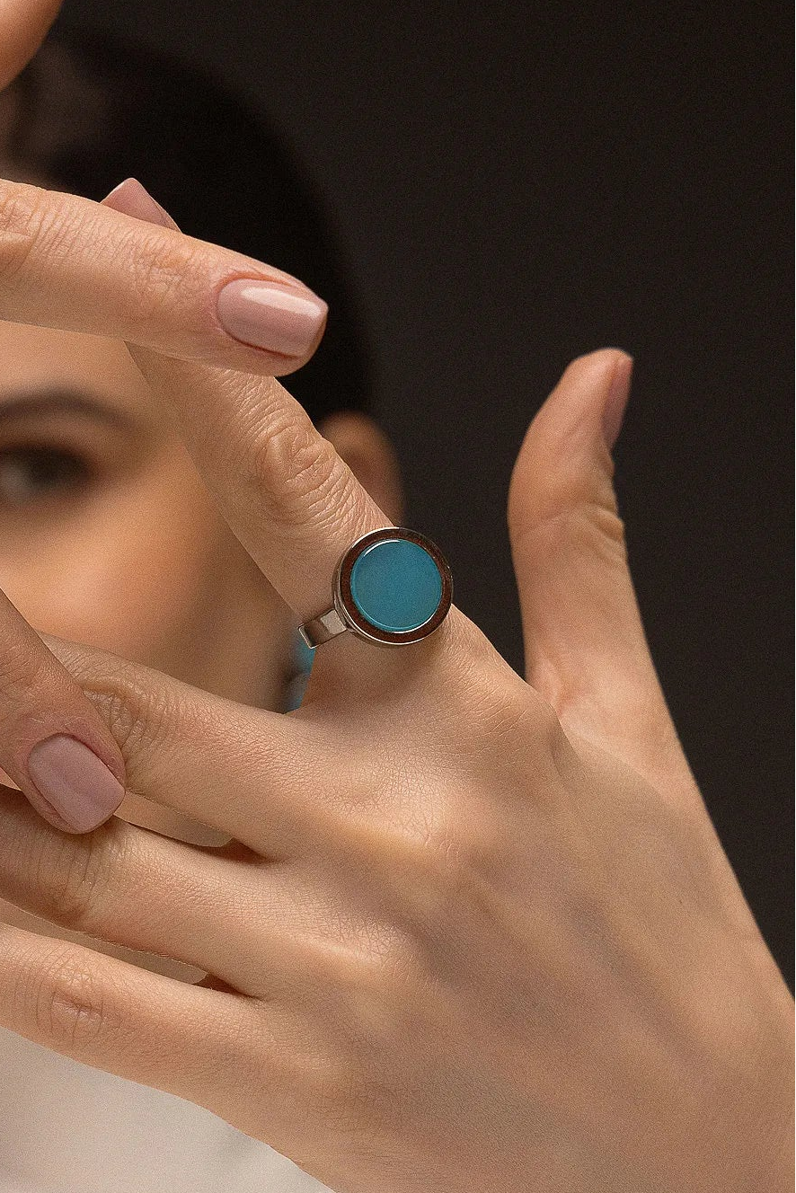 O Anel Eterno - Ágata Azul Céu, da Coleção Singular, une a serenidade das águas à sofisticação do acabamento escuro. A Ágata Azul Céu é reconhecida por promover calma, clareza mental e harmonia nas emoções, criando um contraste moderno e impactante com o metal escuro. Banhado a Ródio Negro, este anel de design contínuo e imponente destaca a suavidade da pedra, sendo a peça ideal para mulheres que buscam um acessório contemporâneo que transmita paz interior com uma personalidade forte.