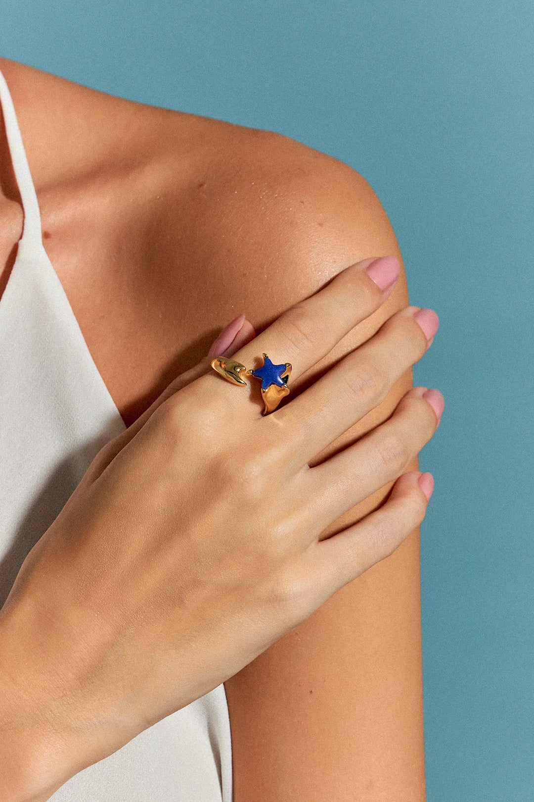 O Anel Serena com Quartzo Azul Anil em Banho de Ouro 18K possui duas estrelas-do-mar que se encontram na mesma direção, simbolizando harmonia e união. O tom profundo do Quartzo Azul Anil, em contraste com o brilho do ouro, cria um visual delicado, mas marcante, que evoca a serenidade do oceano.