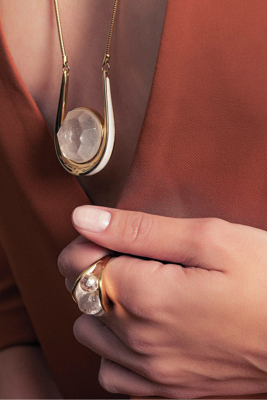 O Anel Sublime em Esmaltado Branco e Cristal de Rocha, com Banho de Ouro 18K, é uma peça clássica e luminosa. O Cristal de Rocha Liso harmoniza-se com o esmalte branco, criando um visual elegante e atemporal com o brilho do ouro.