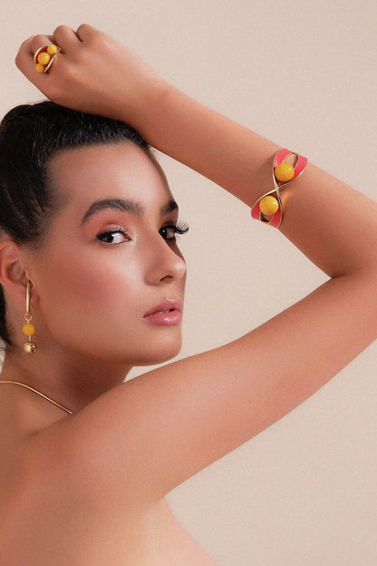 O Anel Sublime em Esmaltado Vermelho e Feldspato Amarelo, com Banho de Ouro 18K, é uma peça vibrante e cheia de personalidade. O Feldspato Amarelo harmoniza-se com o esmalte em tom vermelho, criando um contraste elegante e marcante com o brilho do ouro.