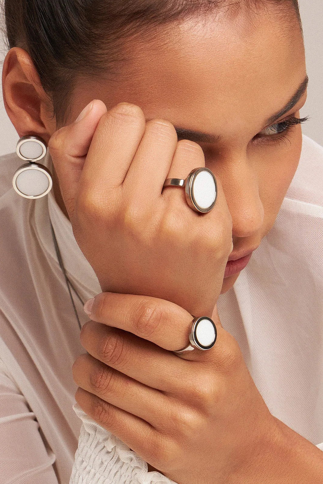 O Anel Único - Porcelana Branca, da Coleção Singular, une a pureza do branco ao mistério do acabamento escuro. A Porcelana Branca simboliza renovação, clareza e paz interior, criando um contraste moderno e sofisticado com o metal escuro. Banhado a Ródio Negro, este anel de design imponente destaca o brilho suave da pedra lisa, sendo a peça ideal para mulheres que buscam acessórios contemporâneos que transmitem serenidade com uma personalidade marcante.