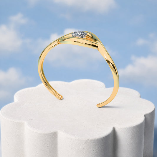 Bracelete Despertar - Drusa Metalizada: sobre pedestal de gesso em forma de nuvem, fundo de céu azul-claro. Semijoia banhada a ouro 18k, coleção Supernova, Aimer Joias