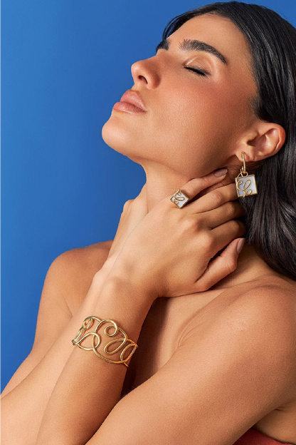 O Bracelete Traços em Banho de Ouro 18K é rígido e de aro aberto, trazendo o mesmo design de linhas livres do brinco, como um desenho contínuo que abraça o pulso. É um lembrete de que o belo não nasce do controle absoluto, mas do gesto que ousa sair do traço e encontra uma nova forma de ser. Peça expressiva e moderna, que incorpora movimento e fluidez.
