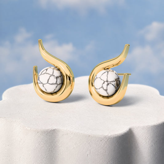 Brinco Órbita - Howlita Branca: sobre pedestal de gesso em forma de nuvem, fundo de céu azul-claro. Semijoia banhada a ouro 18k, coleção Supernova, Aimer Joias