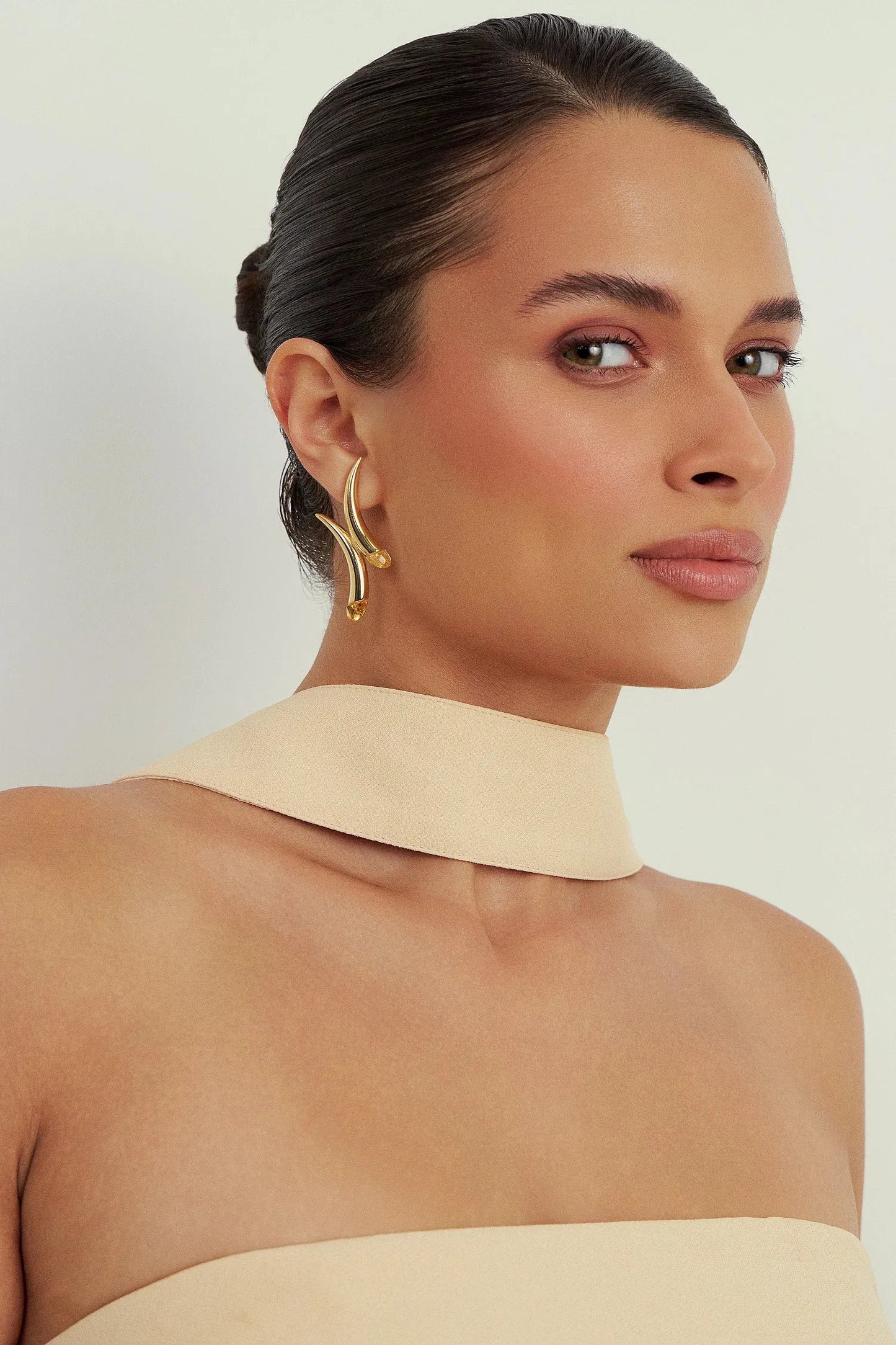 Da Coleção Caminhos, o Brinco Caminhos possui um design fluido e imponente, com curvas que se encontram em um ponto central, simbolizando a união entre trajetórias. As pedras aplicadas nas extremidades, parte do DNA da Aimer, trazem brilho e leveza. Uma joia contemporânea e expressiva, ideal para quem gosta de peças com presença e significado.