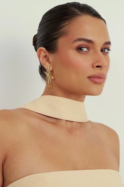 Da Coleção Caminhos, o Brinco Caminhos possui um design fluido e imponente, com curvas que se encontram em um ponto central, simbolizando a união entre trajetórias. As pedras aplicadas nas extremidades, parte do DNA da Aimer, trazem brilho e leveza. Uma joia contemporânea e expressiva, ideal para quem gosta de peças com presença e significado.