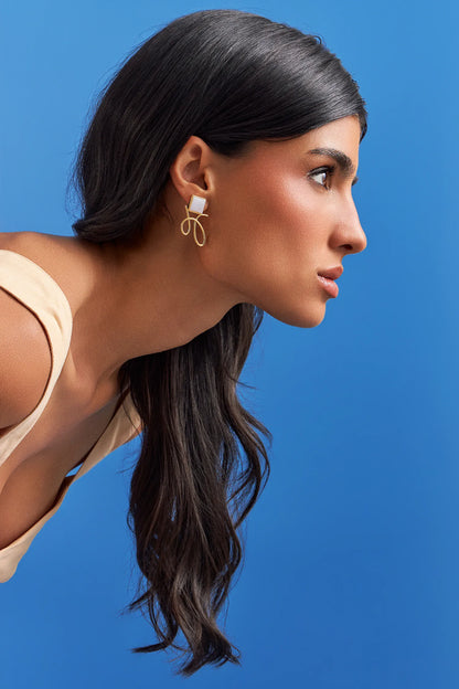 O Brinco Esboço com Ágata Branca em Banho de Ouro 18K traduz o instante em que o traço encontra a forma. Este brinco pequeno e delicado une a pedra quadrada, que atua como ponto de luz, a um toque sutil de traço. A Ágata Branca simboliza serenidade e paz. Com sua estética refinada e minimalista, esta peça é a escolha ideal para adicionar um toque de elegância sutil ao seu visual diário.