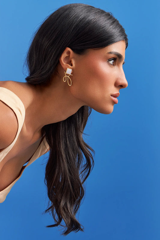 O Brinco Esboço com Ágata Branca em Banho de Ouro 18K traduz o instante em que o traço encontra a forma. Este brinco pequeno e delicado une a pedra quadrada, que atua como ponto de luz, a um toque sutil de traço. A Ágata Branca simboliza serenidade e paz. Com sua estética refinada e minimalista, esta peça é a escolha ideal para adicionar um toque de elegância sutil ao seu visual diário.