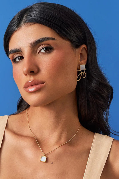 O Brinco Esboço com Ágata Branca em Banho de Ouro 18K traduz o instante em que o traço encontra a forma. Este brinco pequeno e delicado une a pedra quadrada, que atua como ponto de luz, a um toque sutil de traço. A Ágata Branca simboliza serenidade e paz. Com sua estética refinada e minimalista, esta peça é a escolha ideal para adicionar um toque de elegância sutil ao seu visual diário.