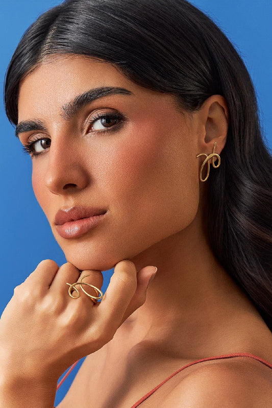 O Brinco Rabiscos em Banho de Ouro 18K traduz a magia do risco que se arrisca a ser algo, com formas orgânicas e minimalistas. Este brinco celebra a beleza do gesto livre e expressivo, sendo uma peça discreta, mas que carrega movimento e significado. É a essência da Coleção Entre o Traço e a Forma.