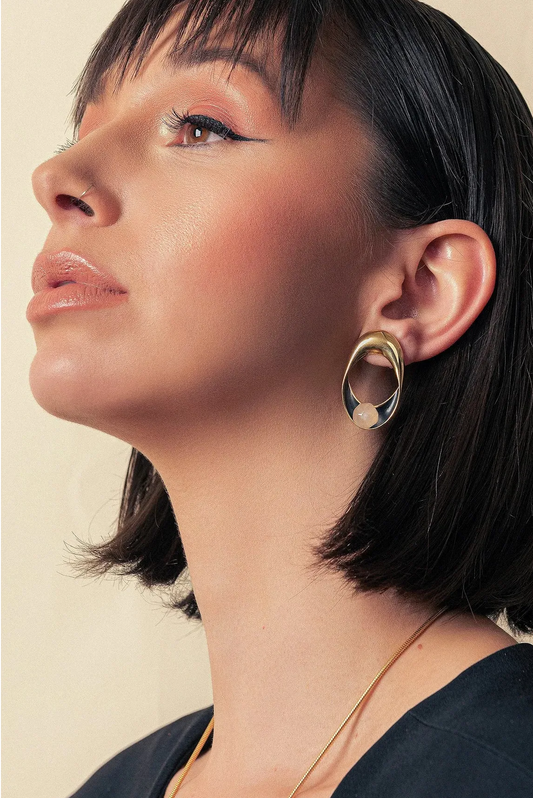 O Brinco Sinergia em Esmaltado Preto e Quartzo Leitoso, com Banho de Ouro 18K, cria um visual clássico de alto contraste. A combinação atemporal do branco leitoso com o esmalte preto é realçada pelo luxuoso acabamento do ouro 18K.