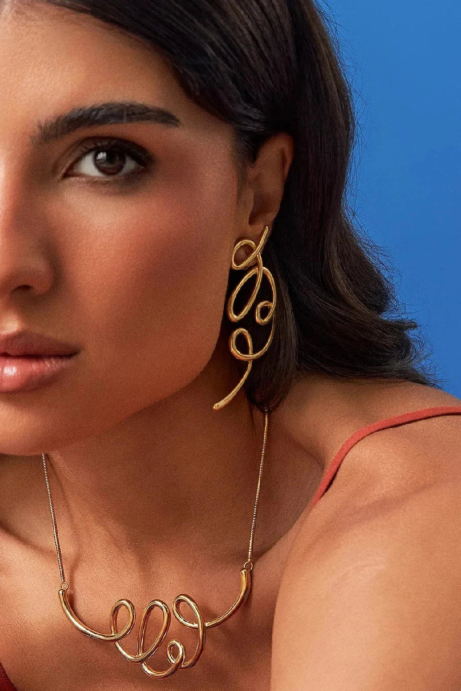 O Brinco Traços em Banho de Ouro 18K é uma joia escultural e assimétrica, inspirada em linhas livres que se encontram, criando volumes fluidos. Um lembrete de que o belo não nasce do controle absoluto, mas do gesto que ousa sair do traço e encontra uma nova forma de ser. São peças leves, expressivas e cheias de movimento.