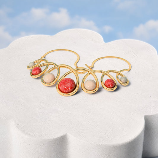 Colar Supernova - Feldspato Vermelho e Quartzo Rosa: sobre pedestal de gesso em forma de nuvem, fundo de céu azul-claro. Semijoia banhada a ouro 18k, coleção Supernova, Aimer Joias