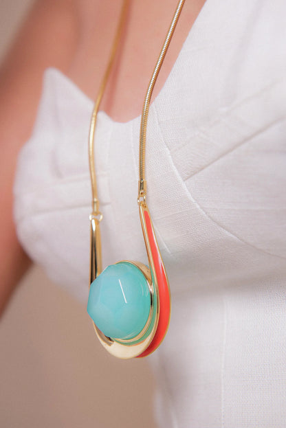 O Colar Magnetismo em Esmaltado Laranja e Ágata Azul Céu, com Banho de Ouro 18K, cria um visual de profundo charme. O azul sereno da Ágata contrasta elegantemente com o esmalte laranja, realçado pelo luxuoso acabamento do ouro 18K.