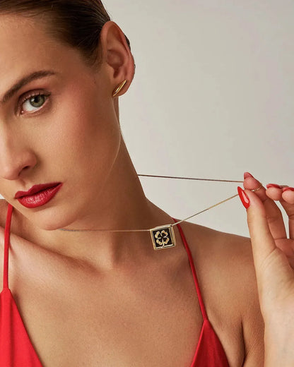 Com um design geométrico e equilibrado, o colar é produzido com Banho de Ouro 18K e possui um pingente com Obsidiana Negra para a sorte da proteção e da força interior, que nos guia mesmo nos dias incertos. O contraste entre o ouro e o preto profundo da pedra natural confere à peça um visual elegante e moderno.